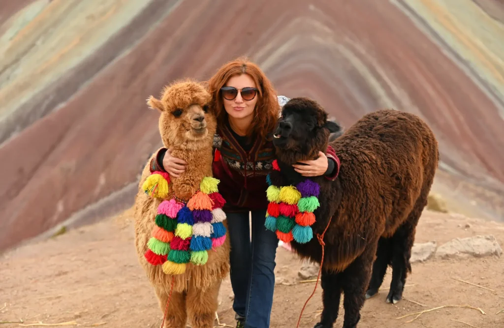 A lady poses for a picture with a couple of alpacas after reaching Winicunca's lookout.