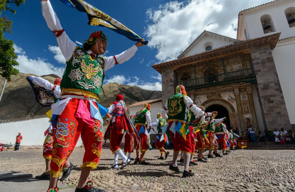 A group of typically dressed dancers celebrate a local festivity in front of Andahuaylillas's church.