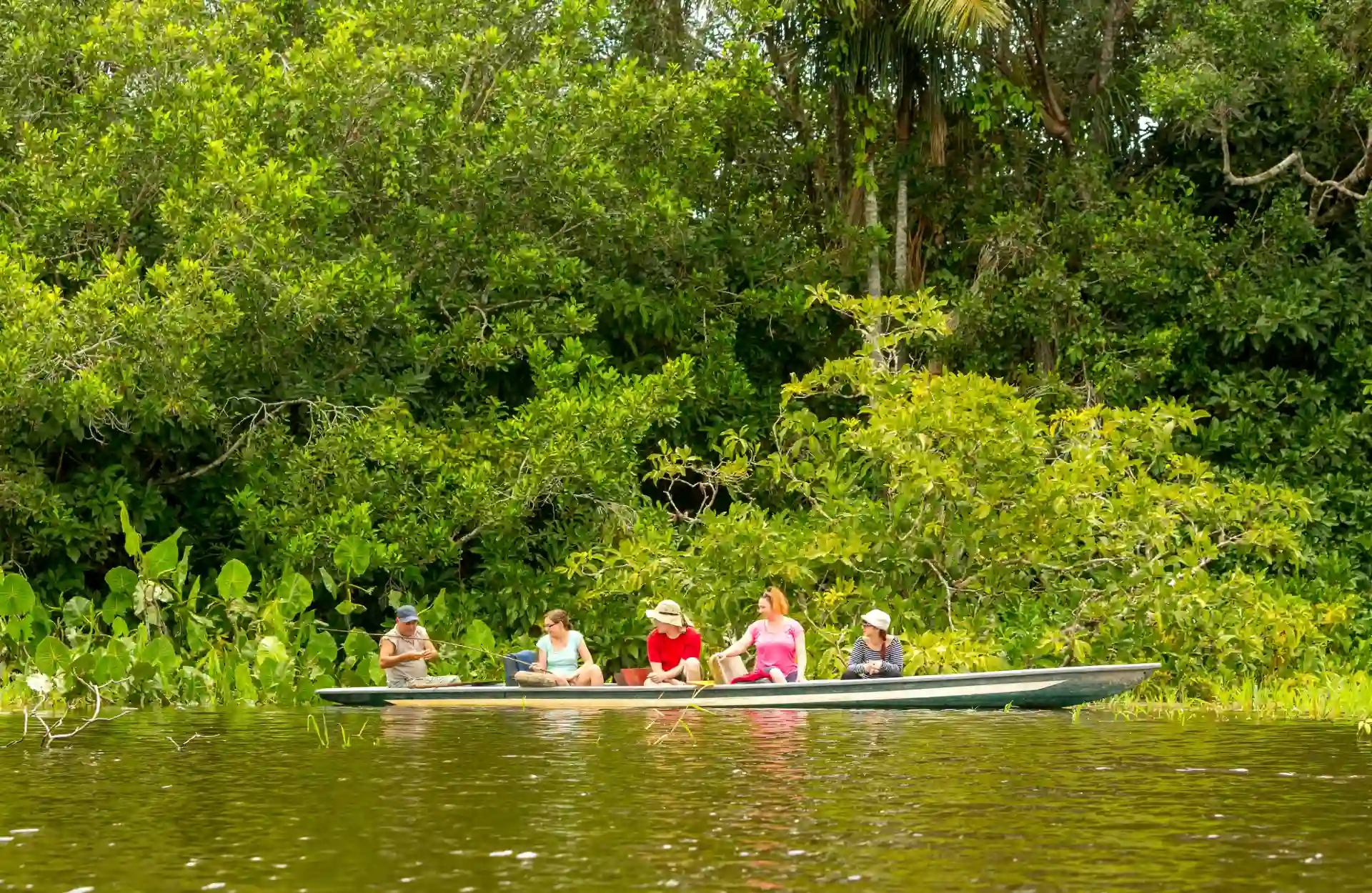 A boat sails with 5 persons on board across the Amazon's river